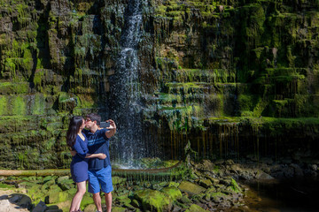 Naklejka na ściany i meble Mixed race couple take selfies at waterfall