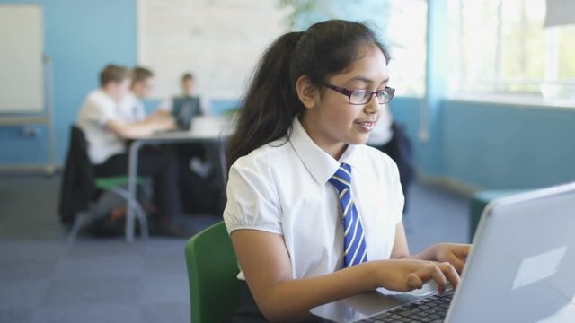  Portrait smiling school girl working on laptop in classroom