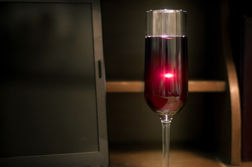 Laptop and red wine in wineglass with lighting behind. Lonelyness or missing date or vacation concept.
