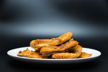 Delicious traditional golden fried banana fritters on white plate with black background isolated