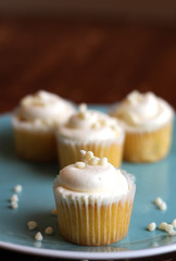 Cupcakes with white frosting arranged on a blue plate on a dark wooden table 