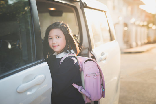 Asian girl in student uniform going to school by car under sunlight