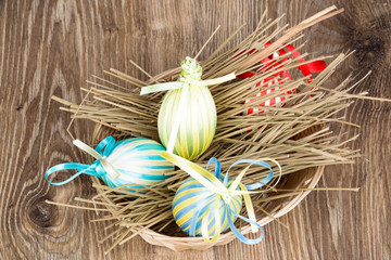 Easter eggs in the wicker on wooden background. Toned image