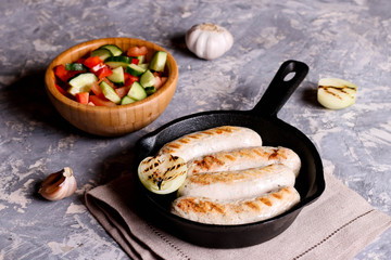 Sausages in rustic pan with onion. Frying pan with fried sausage and vegetables