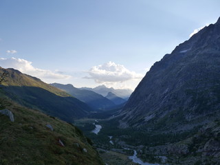 Sunset mountain valley with small river and steep mountains