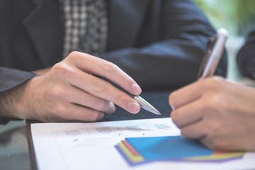 Hand of business people with pen and data sheet at meeting  