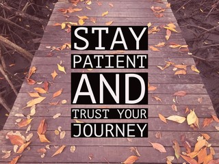 Inspirational motivational quote “stay patient and trust your journey” on wooden walkway with...