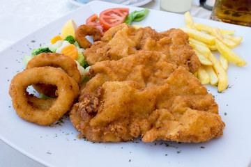 Vienna schnitzel with onion rings and quickly boiled vegetables served at the restaurant in Sombor, Serbia