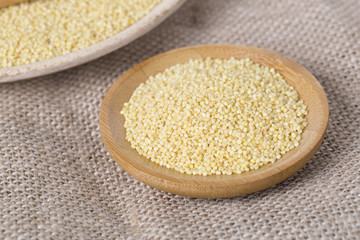 Yellow millet seeds in a wooden bowl on the table
