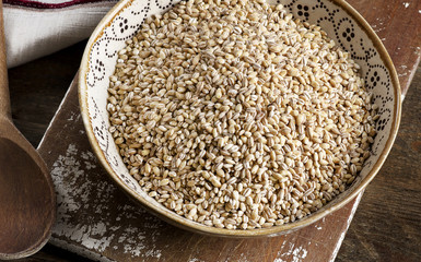 Barley in a bowl on a rustic wooden board.