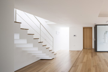 white empty living room with stair, wood floor, window, pendant lighting.