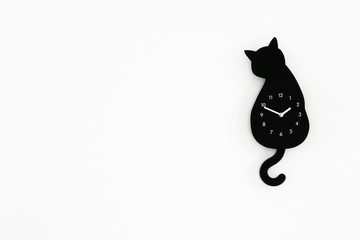 Back cat clock on white wall background 