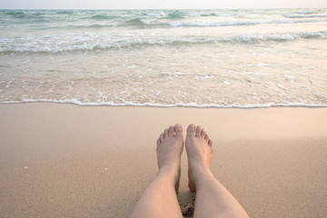 foot of human on sand and soft wave on the sea.