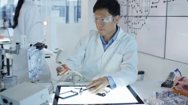  Electronics engineers working in lab building & testing electronic devices