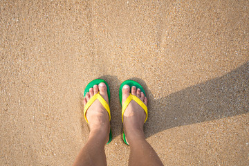 foot and sandal on the sand beach.