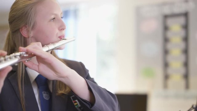  Close up portrait of teen girl playing the flute in school music lesson