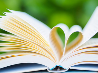 book on table in garden with top one opened and pages forming heart shape