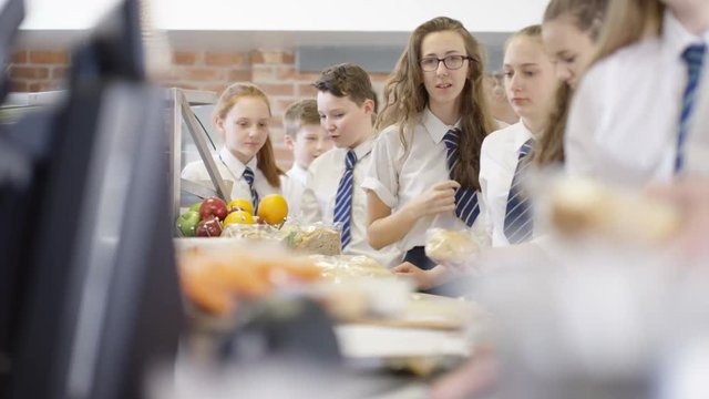  Children in school cafeteria queuing up at electronic till to scan food items