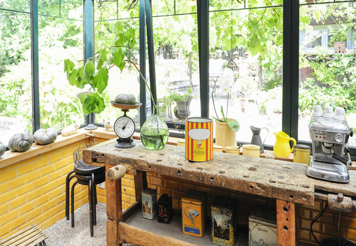 Kitchen and patio overlooking a garden with old wooden bench, scale and old boxes in a country house atmosphere