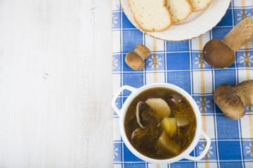 Soup of wild mushrooms on a wooden table.