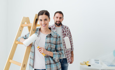 Happy couple painting their new home - obrazy, fototapety, plakaty