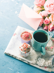 Mother's day Valentine concept muffins with hearts sprinkles and cup of tea on napkin. Flowers