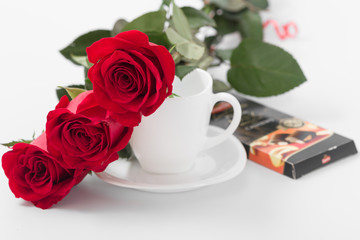 Red roses with coffee cup of white color on a white background.