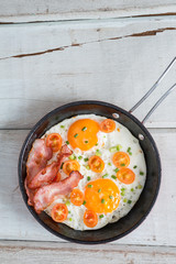 Pan of fried eggs, bacon and tomato. Top view.