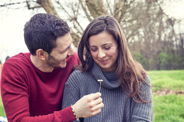 lover boy gives a daisy to her girlfriend in the park