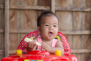 Fototapeta na wymiar Cute asian baby toddler girl sitting on red stroller.