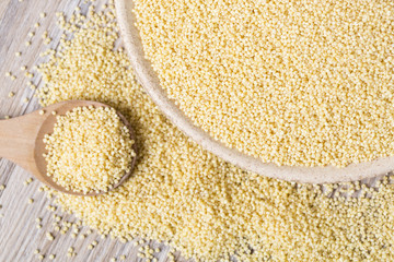 Yellow millet seeds in a wooden bowl on the table