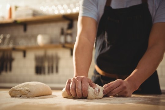 Chef kneading dough in commercial kitchen