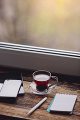 Smartphone and cup of coffee on the wooden table.