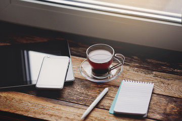 Smartphone and cup of coffee on the wooden table.