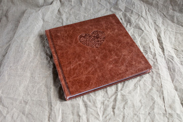 Photo book with a cover of genuine leather. Brown color with decorative stamping . Linen fabric background  