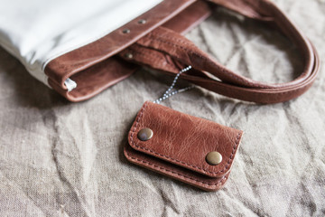 Leather accessory. A purse from genuine leather. Closeup at handmade tanned leather minimalist wallet. Linen fabric background  