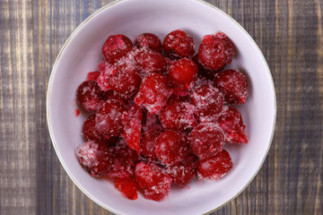Frozen cherry berries in a white cup on the table. Close-up image