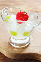 Juicy strawberry in a glass container with ice on a wooden surface. Selective focus