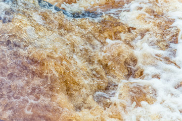 Yellow-brown splashes of water from the waterfall of Akhvenkoski in Karelia