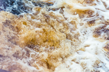 Naklejka na ściany i meble Yellow-brown splashes of water from the waterfall of Akhvenkoski in Karelia