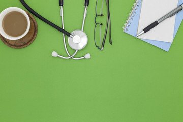 Stethoscope with notebook ,pen, white paper ,coffee cup,glasses,Medical background concept.