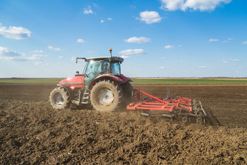 Obraz premium Farmer in tractor preparing land with seedbed cultivator as part of pre seeding activities in early spring season of agricultural works at farmlands.