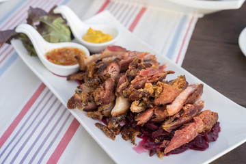 Slice of Fried pork leg with purple cabbage and spicy sauce.