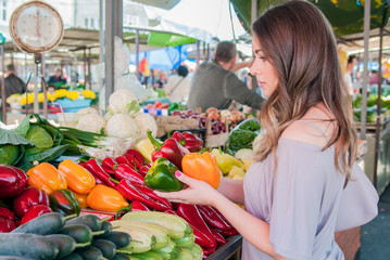 Woman buying vegetables in organic section of green market. woman selecting pepper while in a supermarket