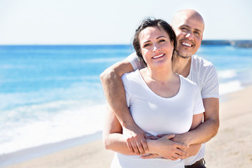 Fototapeta premium Couple gladly hugging each other and enjoying the beach