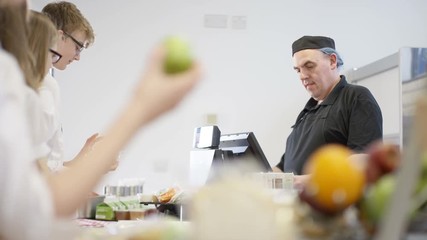  Children in school cafeteria queuing up at electronic till to scan food items