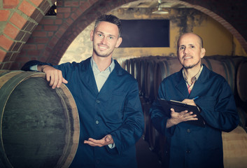 Fototapeta na wymiar Two smiling men winery employees writing note