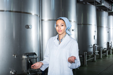 Young woman wearing coat standing in large wine cellar