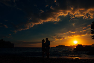 Silhouette of a newlywed couple at the sea at sunset. Wedding in Montenegro. Silhouettes of the couple, the bride and groom.