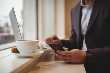 Businessman using mobile phone in coffee shop